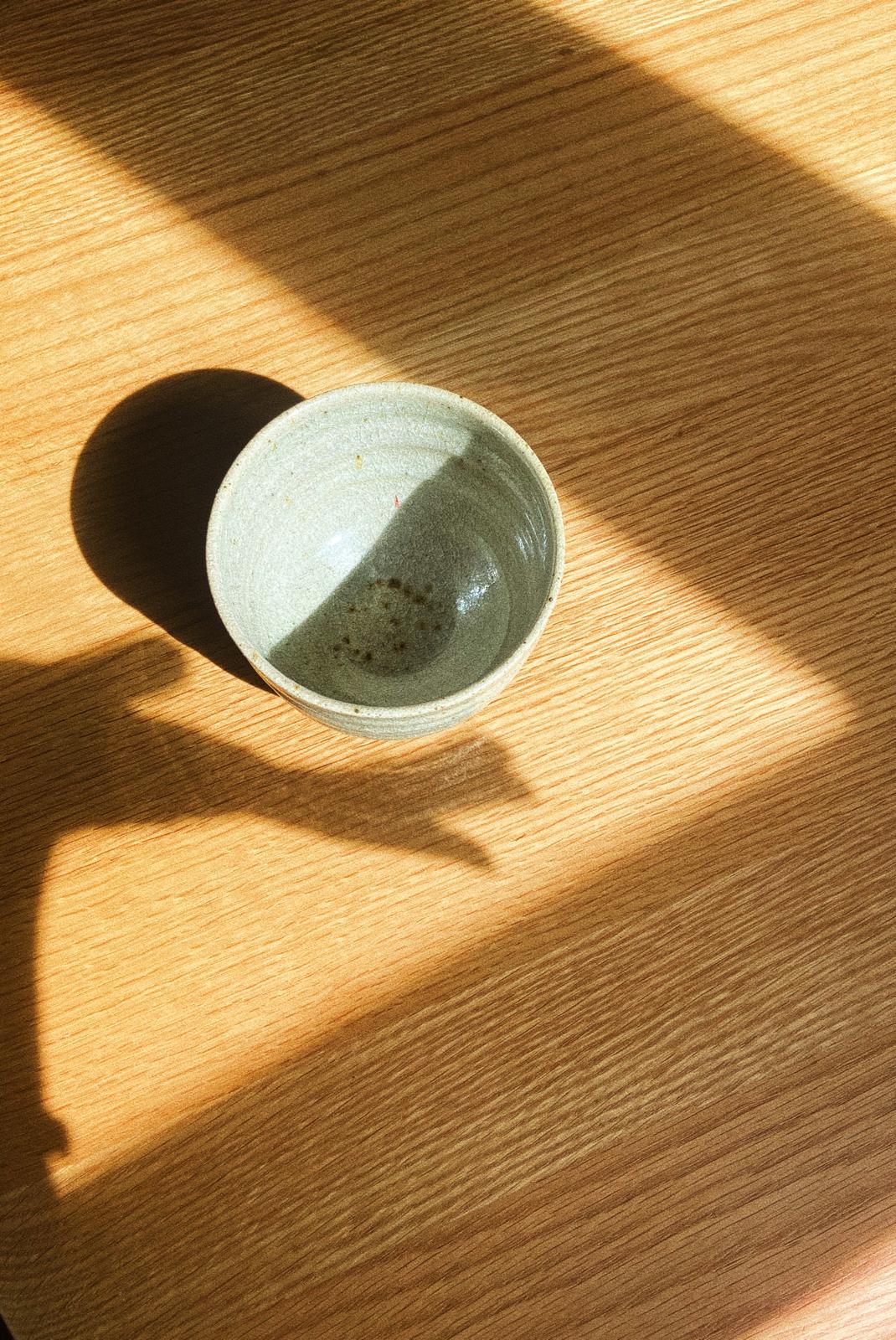 Ceramic cacao bowl on a wooden surface with sunlight casting shadows